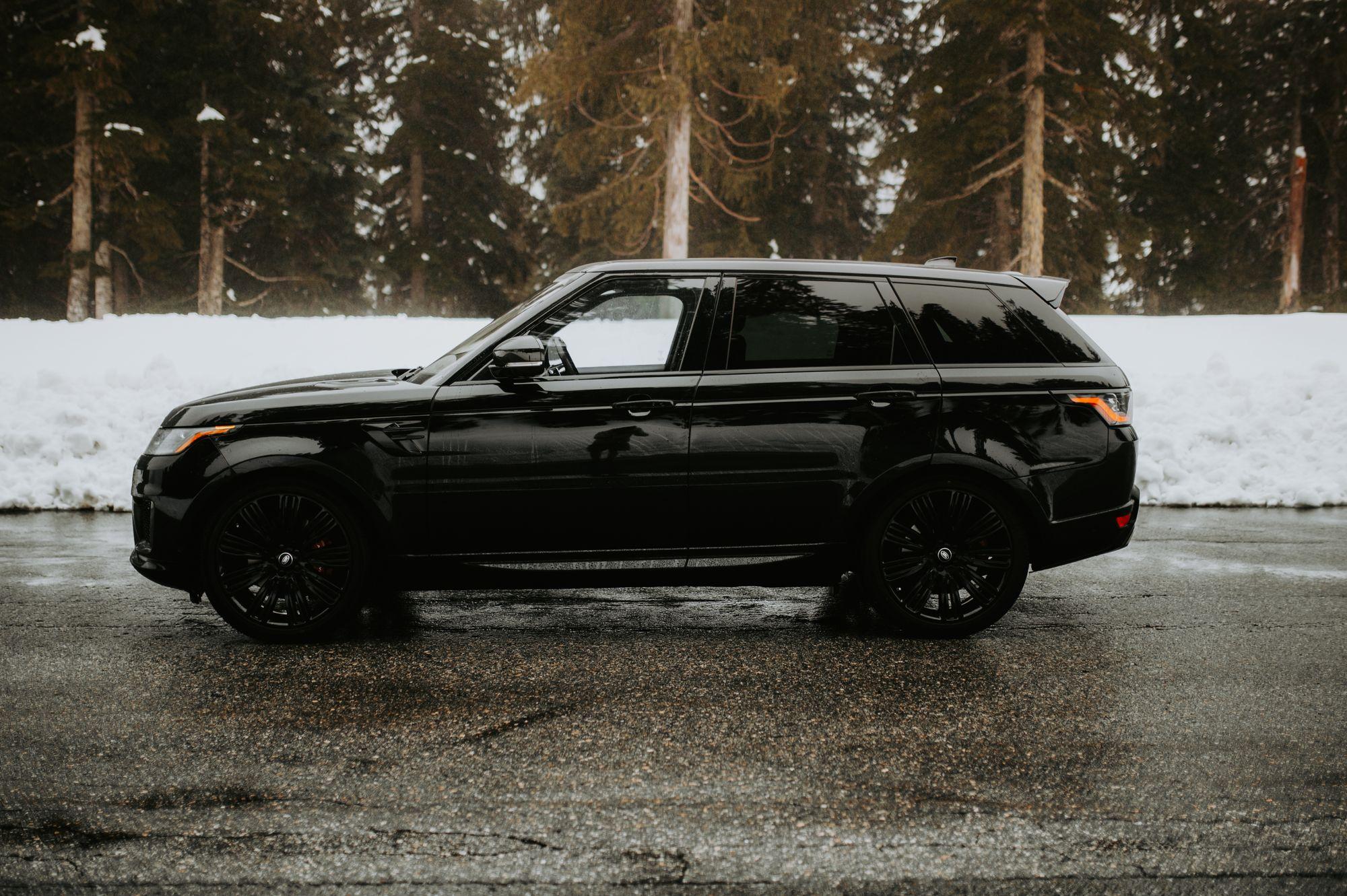 Black Range Rover Sport beside a snowy treeline